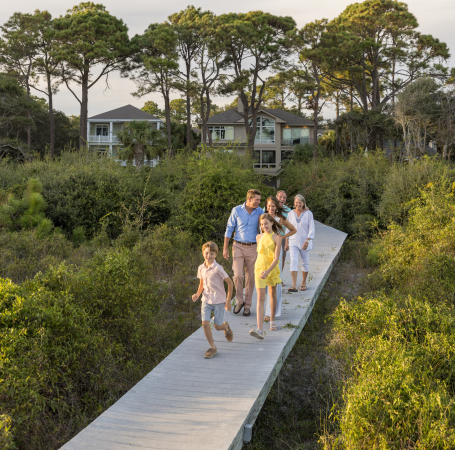 family walking down a dock from their beachfront home