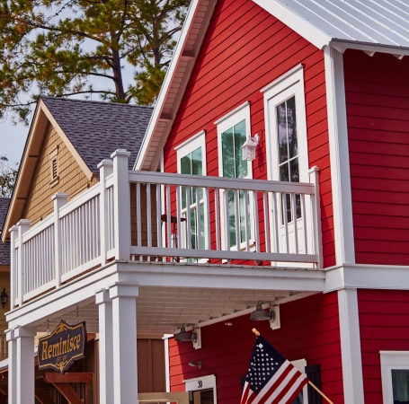 red house with large balcony and flag hanging outside the front door